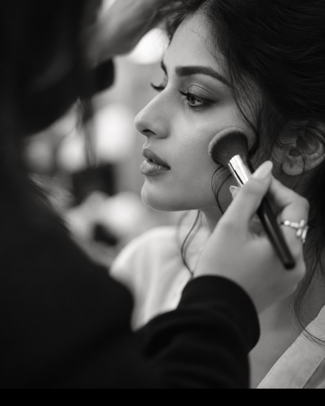 A make-up artist presses powder onto a model's cheek with a fluffy brush