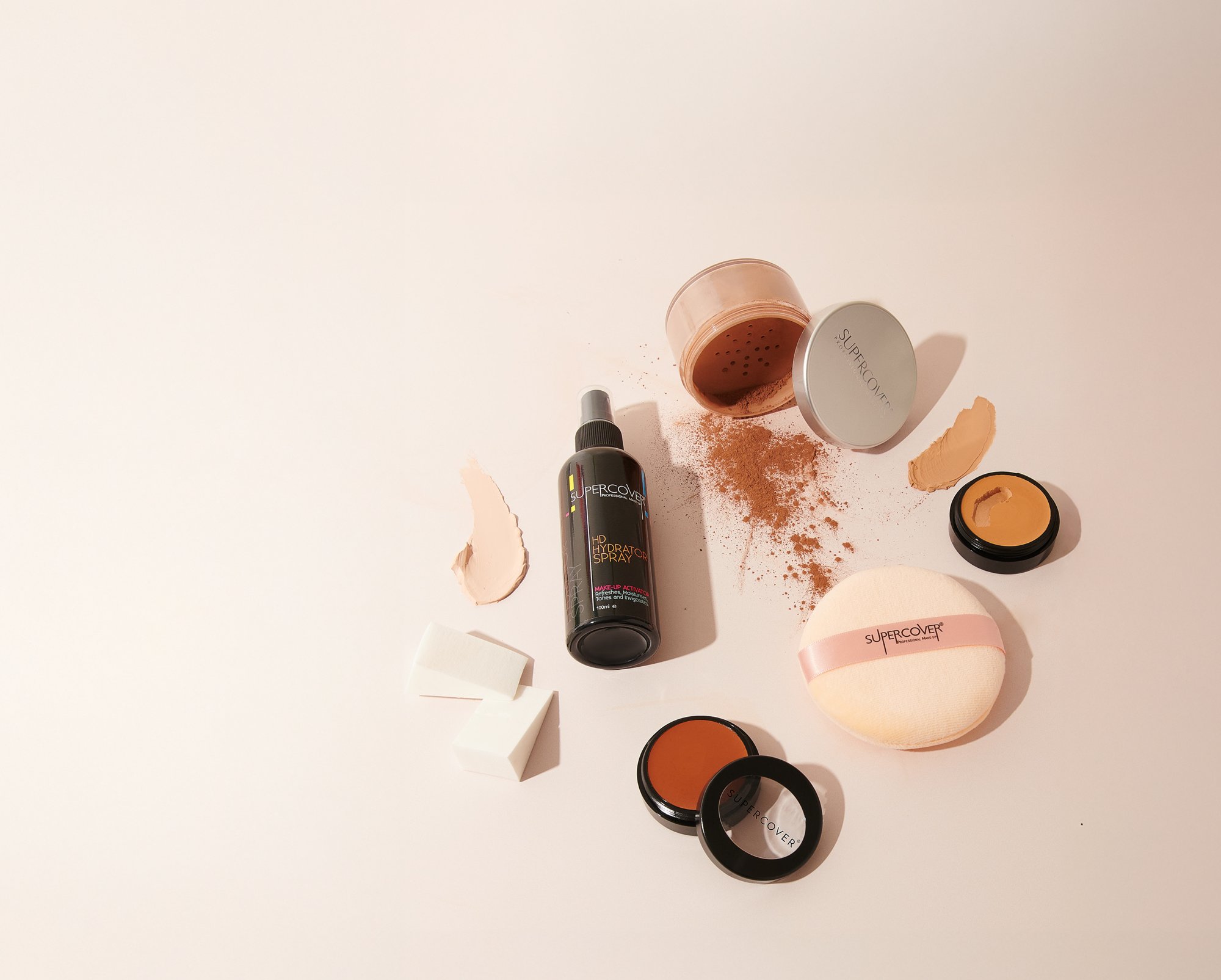 A make-up artist working SUPERCOVER cream foundation from a steel palette